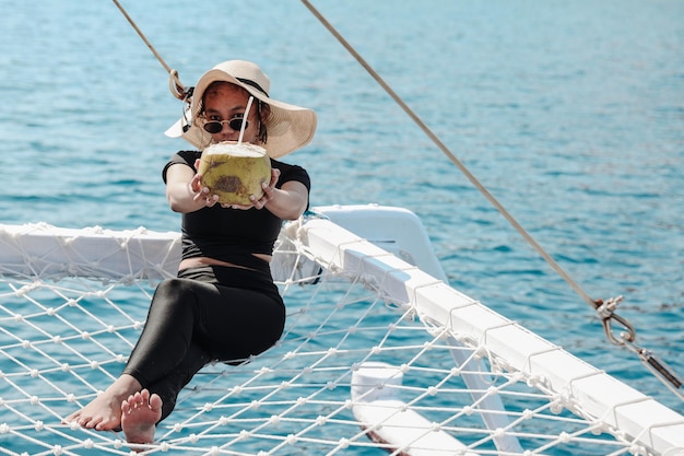 Une fille appréciant la noix de coco pendant les vacances d'été sur la mer