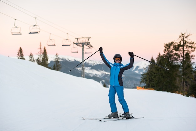 Fille appréciant les vacances de ski debout sur la montagne enneigée et leva les mains vers le haut