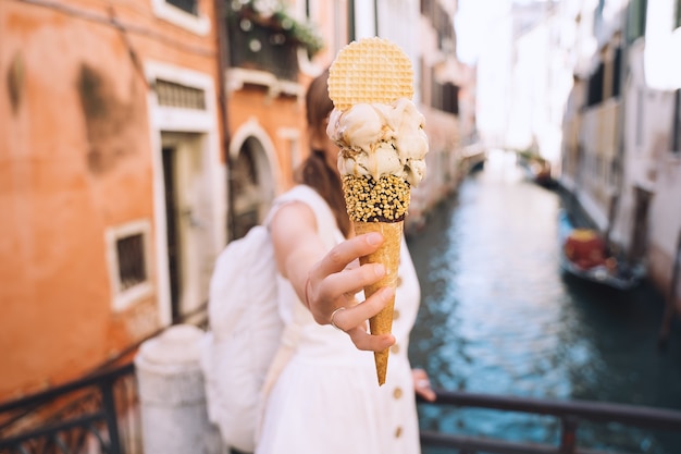 La fille apprécie le gelato italien beau et délicieux dans le cône de gaufre sur les ponts scéniques de Venise