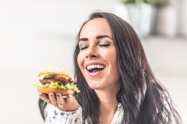 La fille apprécie l'odeur d'un hamburger fraîchement préparé dans sa main.