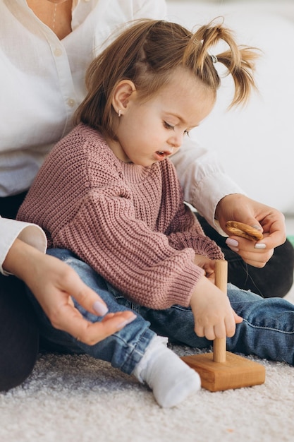 La fille apprend les couleurs en jouant avec des figurines humaines colorées de jouets cylindriques en bois et en les plaçant dans des tasses de la couleur appropriée L'enfant est heureux d'avoir terminé la tâche correctement