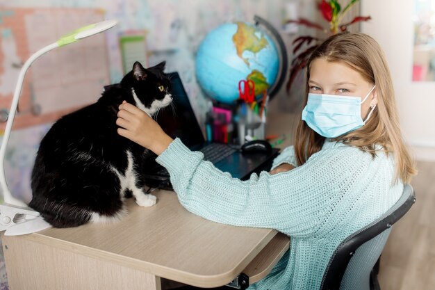 Fille d'apprentissage à distance caressant un chat à la maison