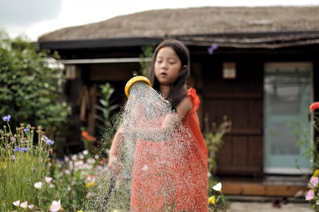 Une fille arrose des plantes dans le jardin.