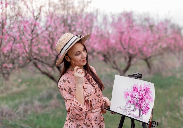 Photo fille artiste peint un verger de pêchers dans un printemps de verger de pêchers