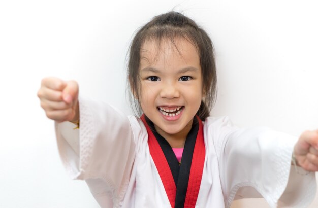 Fille asiatique affichant le poinçon de Taekwondo sur fond blanc.