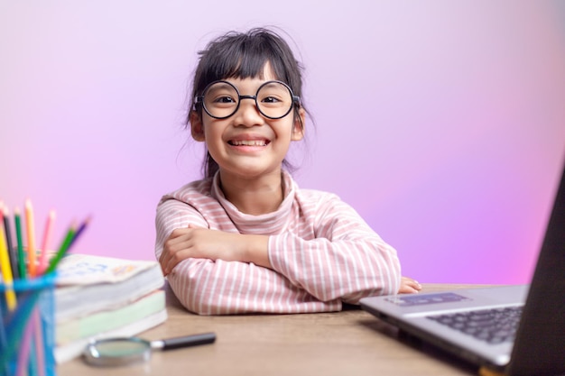 Photo fille asiatique assise et étudiant à la maison sur un ordinateur portable pour étudier à domicile pendant le verrouillage de la pandémie de covid-19. enseignement en ligne, enseignement à domicile