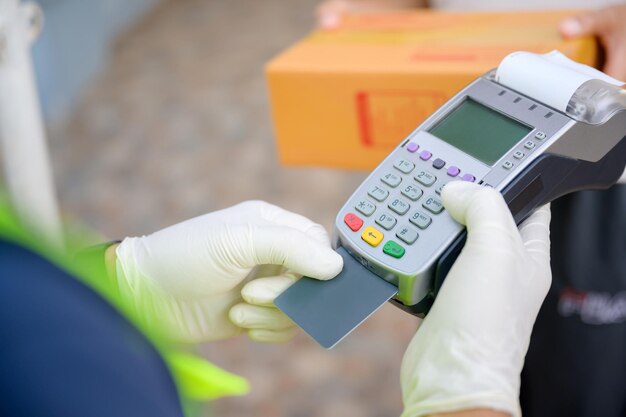 Une fille asiatique avec une carte de crédit a reçu un colis d'un livreur. La femme a payé le livreur. par carte de crédit et terminal de point de vente sans fil pour le paiement par carte