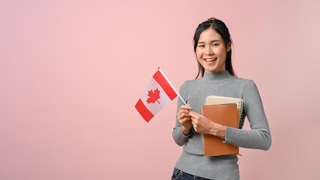 Fille asiatique confiante montrant le drapeau du Canada sur le concept d'éducation de fond isolé rose