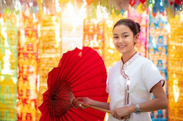 Fille asiatique en costume traditionnel du nord et parapluie rouge