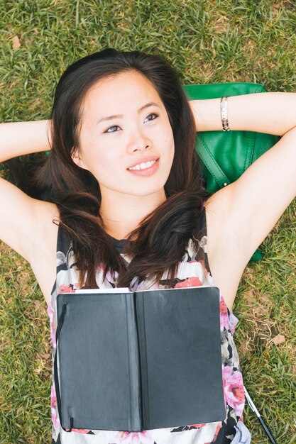 Fille asiatique couchée sur l&#39;herbe au parc