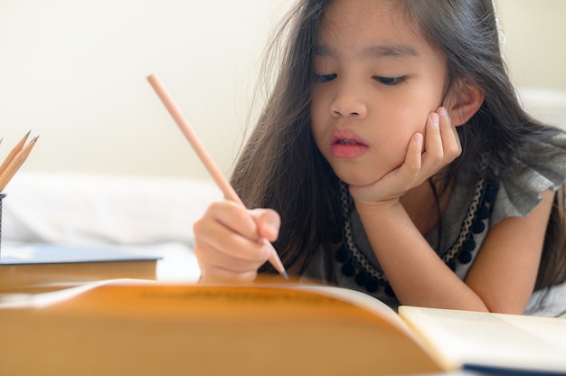 Fille asiatique écrit avec un crayon et un cahier