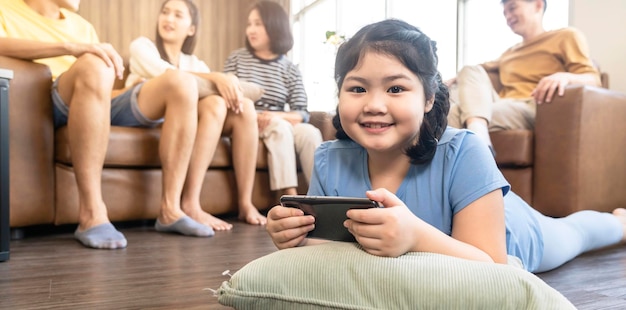 Fille asiatique enfant concentré focus main utiliser le jeu de smartphone en ligne jouer avec une quarantaine joyeuse et amusante rester à la maison dans le fond intérieur de la maison de salon