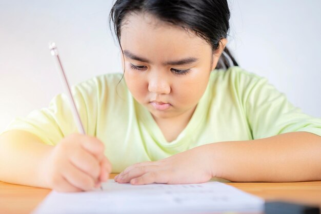 Une fille asiatique fait ses devoirs en faisant des exercices d'amélioration des compétences Concept de retour à l'école