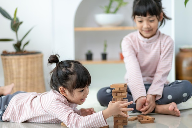 Fille asiatique de fratrie jouant des piles en bois à la maison