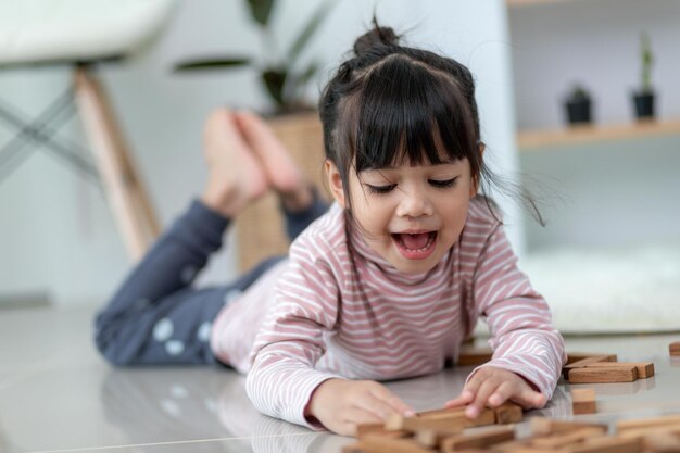 Fille asiatique de fratrie jouant des piles en bois à la maison