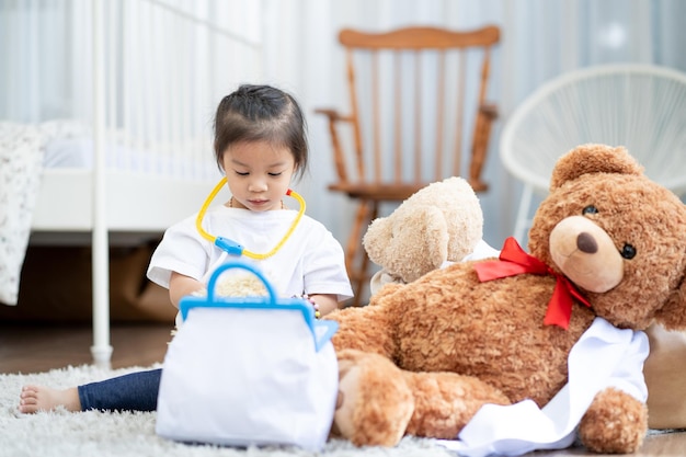 Une fille asiatique heureuse jouant au médecin ou à l'infirmière écoutant un stéthoscope pour jouet