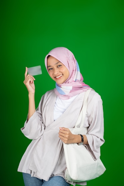 Fille asiatique en hijab souriant tout en tenant une carte de guichet automatique