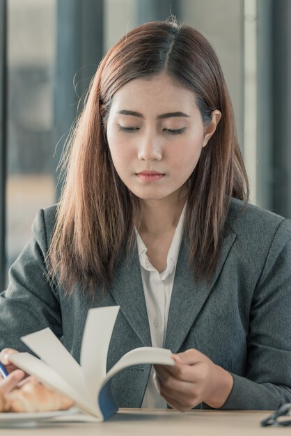 Fille asiatique en lisant un livre sur le bureau.