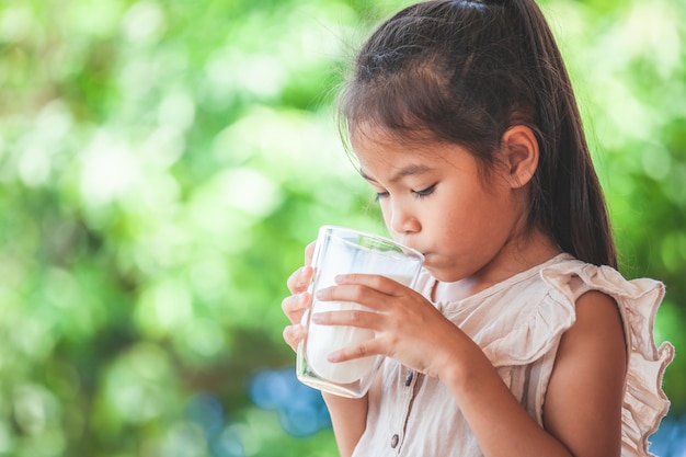 Fille asiatique mignonne boit un lait de verre