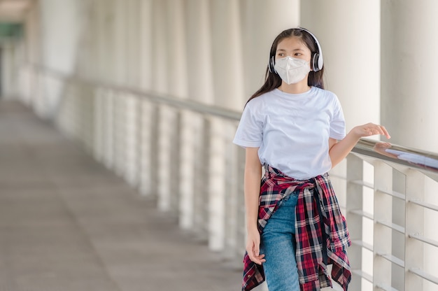 Une fille asiatique portant un masque marche sur une passerelle.