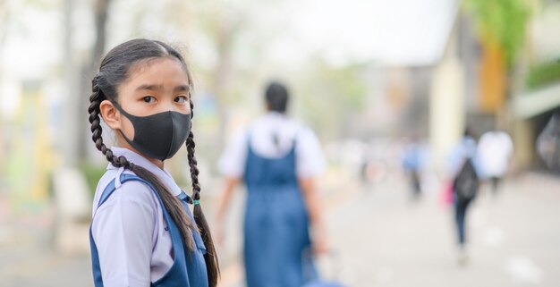 Une fille asiatique porte un masque pour protéger la poussière et la pollution de l'air des PM 2,5