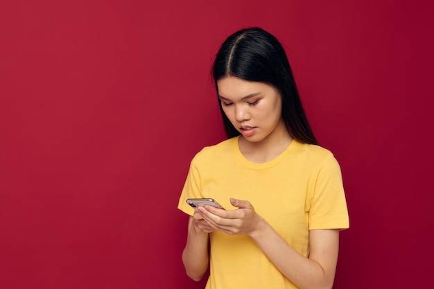 Fille asiatique posant sur un fond coloré avec un téléphone