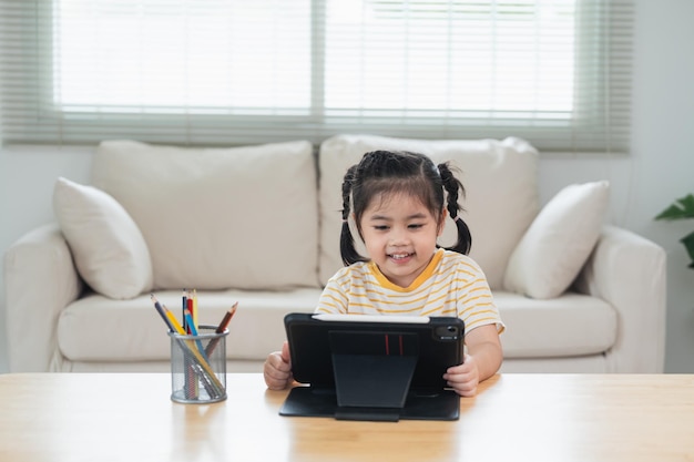 Fille asiatique regardant et touchant sur un écran blanc à l'écran de la tablette concept d'enfants surstimulés avec attention Trop de temps d'écran Jolie fille regardant des vidéos pendant la télévision Concept de dépendance à Internet