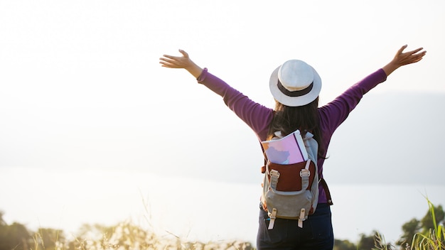 Fille asiatique sac à dos, admirant le coucher de soleil sur la montagne. Détendez-vous en voyage concept de vacances