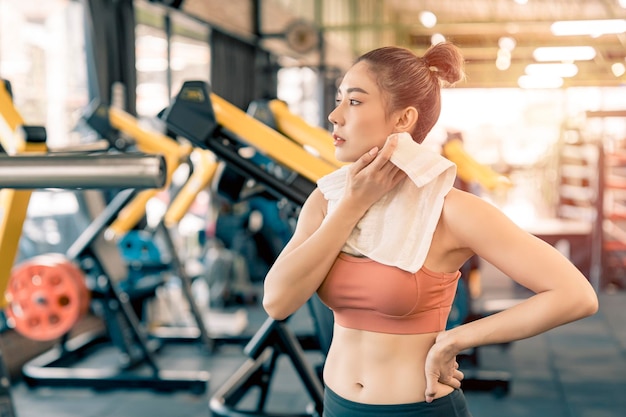 Photo fille asiatique se reposant de l'exercice dans la salle de fitness et sueur sur son visage