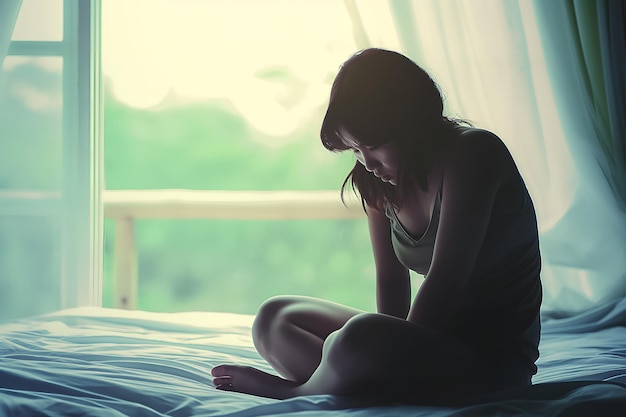 Une fille asiatique se sent triste et seule dans la chambre à coucher sous une faible lumière.
