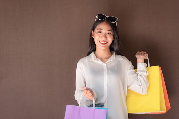 fille asiatique souriante avec des sacs à provisions en train de faire du shopping expression détendue