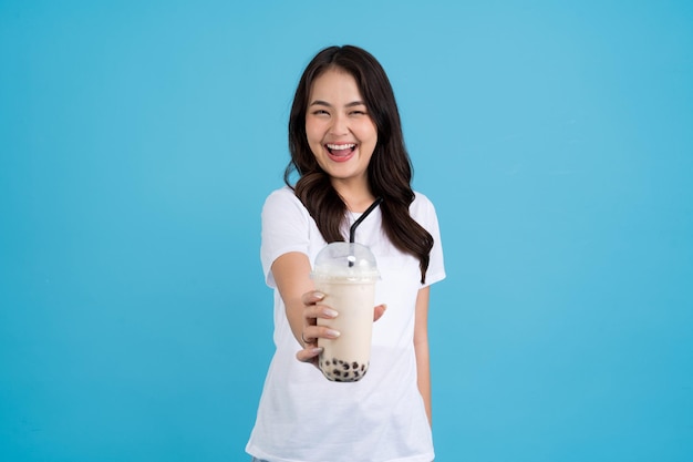 Fille asiatique tenant une tasse de thé au lait perlé avec un sourire amusant et bonheur