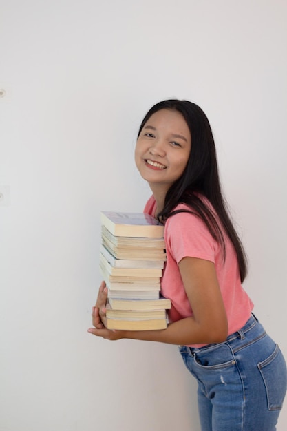 Une fille asiatique tient un livre sur son bras sur fond de whiye