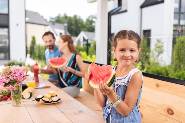 Fille assez positive souriant tout en mangeant une pastèque