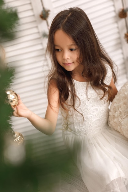 Une fille assez souriante décore le sapin de Noël à la maison