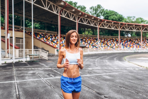 Fille assez sportive en cours d&#39;exécution et d&#39;écoute de la musique en plein air.