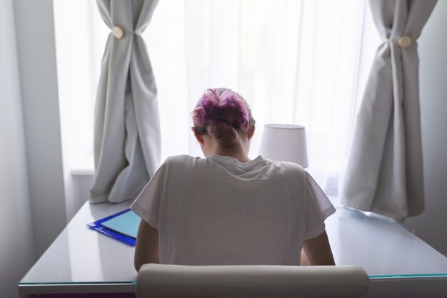 Fille assise au bureau près de la fenêtre