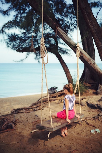 Photo une fille assise sur une balançoire à la plage