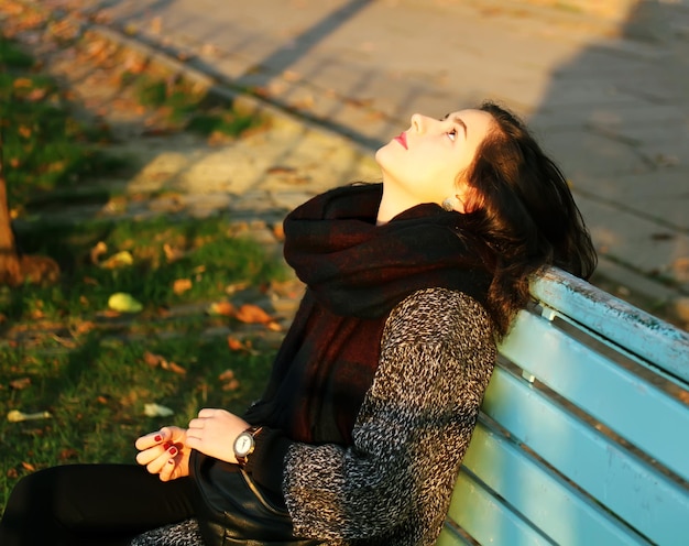 Fille assise sur le banc à l'automne dans le parc