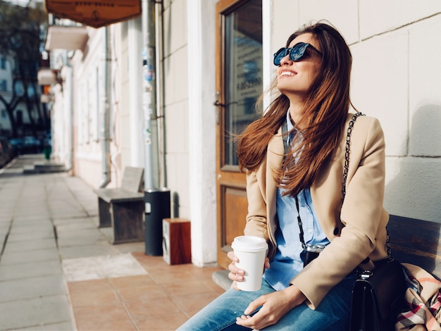 Fille assise sur le banc et boire du café