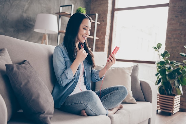 fille assise sur un canapé en regardant le téléphone