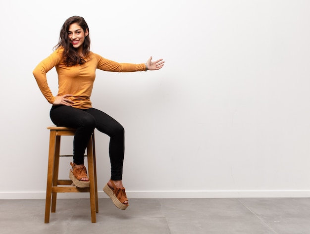 fille assise sur une chaise tout en montrant quelque chose avec la main