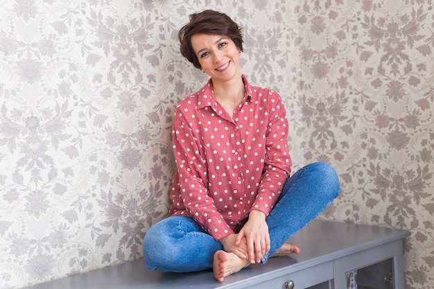 Fille assise sur une commode à la maison.