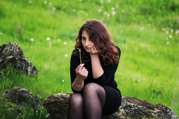 Fille assise dans les bois sur un rocher en été