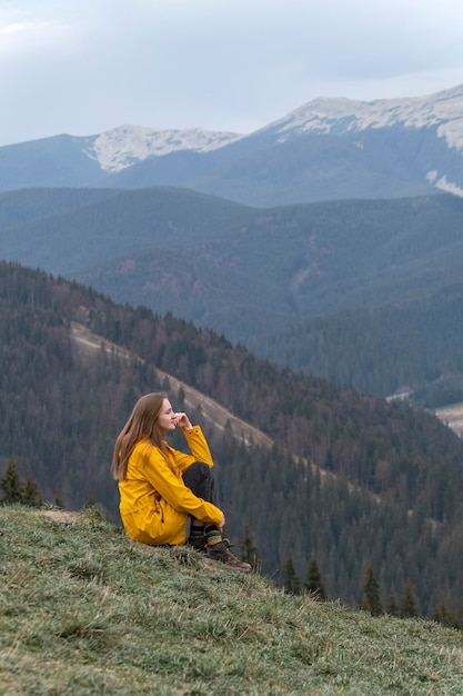 Fille assise sur le flanc de la montagne Jeune femme dans les montagnes profitant de l'air pur Vue verticale