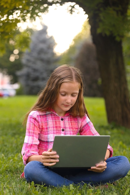 Fille Assise Sur L'herbe Avec Ordinateur Portable