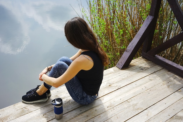 Fille Assise Sur Une Jetée En Bois Près De L'eau.