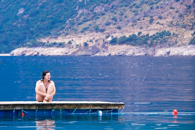 Fille assise sur une jetée près de la mer