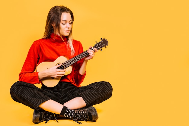 Fille assise jouant de l&#39;ukelele