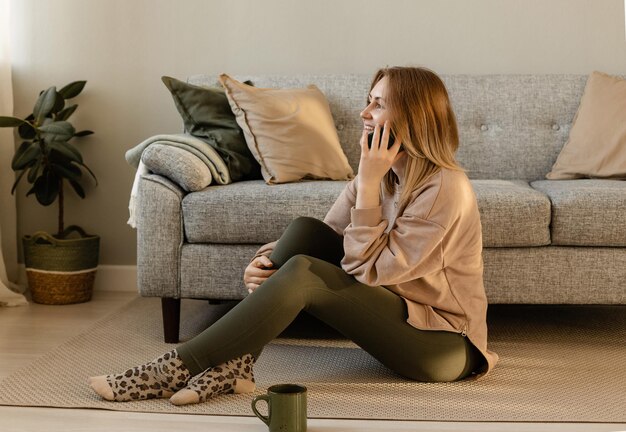 Fille assise à la maison et parlant au téléphone